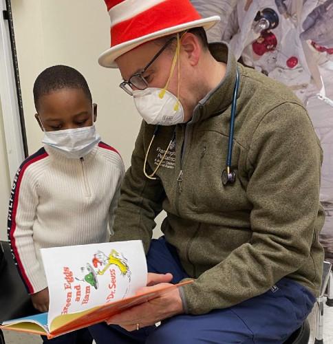 a doctor reading a book to a kid while wearing a dr. seuss hat